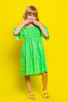 I will not say anyone. Frightened blonde child girl kid closing mouth with hands, looking intimidated scared at camera, gestures no, refusing to tell terrible secret, unbelievable truth. Vertical shot