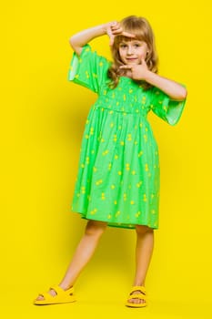 Blonde child girl kid photographer gesturing picture frame with hands, looks through fingers, focusing on interesting moment, imitating zoom and cropping nice image. Little preteen children. Vertical
