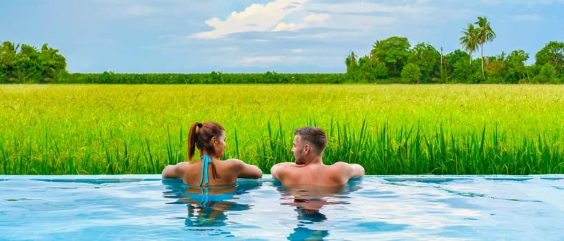 a couple of men and women in front of a Bamboo hut homestay farm, with Green rice paddy fields in Central Thailand with a small plunge pool