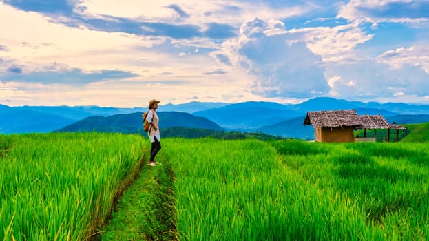 Terraced Rice Field in Chiangmai, Thailand, Pa Pong Piang rice terraces, green rice paddy fields during rain season. Asian woman walking hiking in the mountains at sunset