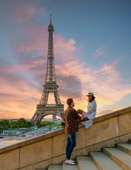 Young couple by Eiffel Tower at Sunrise, Paris Eifel Tower Sunrise man woman in love, valentine concept in Paris the city of love. Men and women visiting the Eiffel Tower.