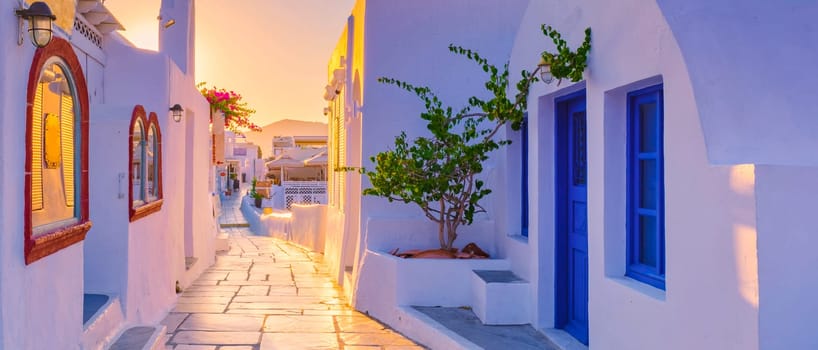 Sunset with white churches and blue domes by the ocean of Oia Santorini Greece.