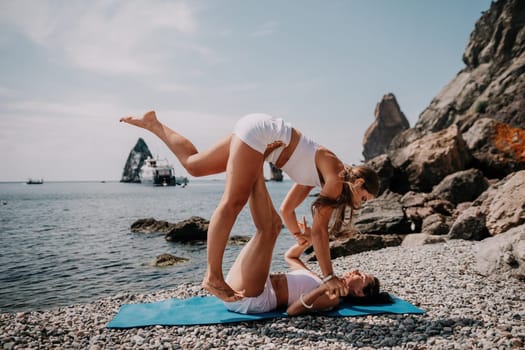 Woman sea yoga. Back view of free calm happy satisfied woman with long hair standing on top rock with yoga position against of sky by the sea. Healthy lifestyle outdoors in nature, fitness concept.