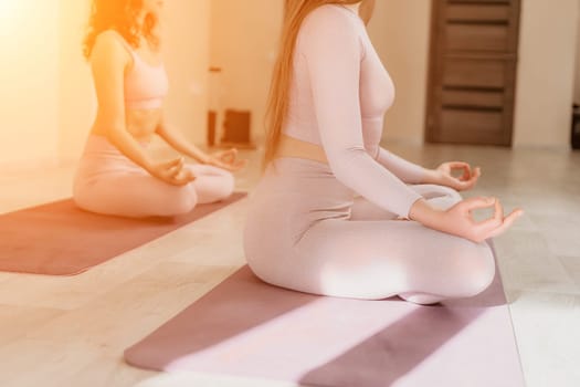 Young woman with long hair in white swimsuit and boho style braclets practicing outdoors on yoga mat by the sea on a sunset. Women's yoga fitness routine. Healthy lifestyle, harmony and meditation