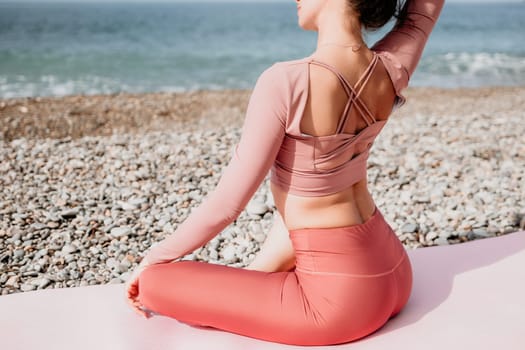 Middle aged well looking woman with black hair doing Pilates with the ring on the yoga mat near the sea on the pebble beach. Female fitness yoga concept. Healthy lifestyle, harmony and meditation.