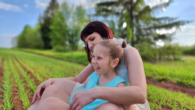 Happy mother and daughter enjoying rest, playing and fun on nature in green field. Woman and girl resting outdoors in summer or spring day