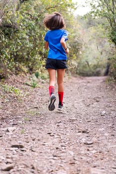rear view of a girl practicing trail running in the forest, concept of sport in nature and healthy lifestyle, copy space for text