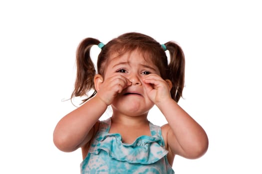 Sad unhappy crying cute little young toddler girl wiping tears, isolated.
