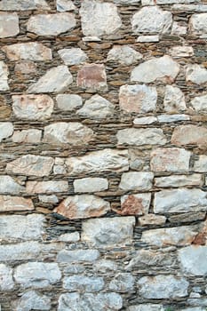 Traditional greek wall by rocks, used as background