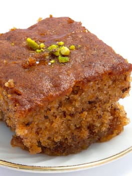 A piece of walnut cake on a plate, isolated on white background