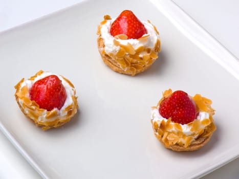 Three tasty strawberry tarts on a sqare plate, closeup