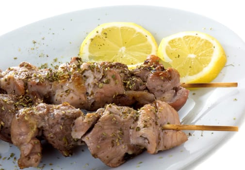 A plate with two souvlaki and lemons, isolated on white background