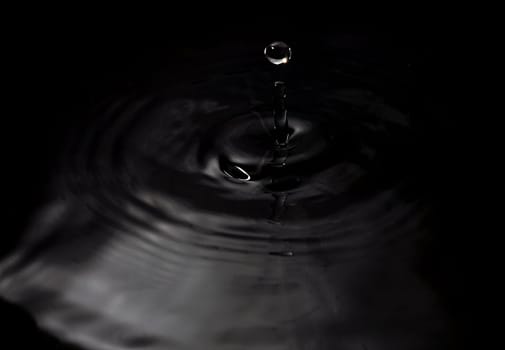 A water drop fall in water, on black background