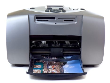 A small gray inkjet printer is printing a photo, isolated on white background