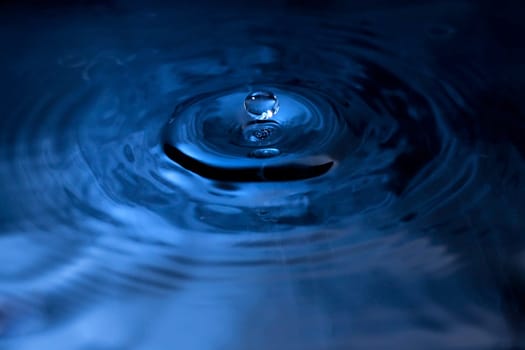 A water drop fall in water, photographed with blue filter