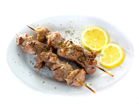 A plate with original greek Souvlaki (also known as Kalamaki) and lemons, isolated on white background