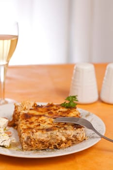 Pastitsio greek food on a table, wine alcohol drink salt, feta cheese and pepper