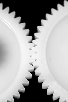Two white connected cogwheels on black background