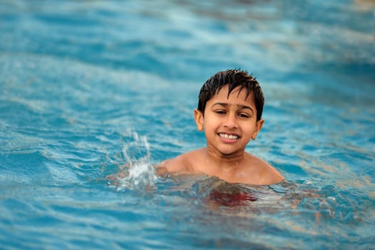 an handsome young indian kid swimming in the pool