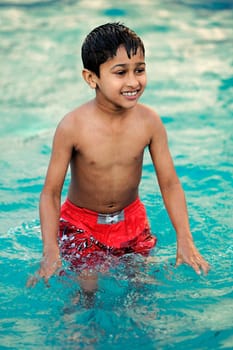 an handsome young indian kid swimming in the pool