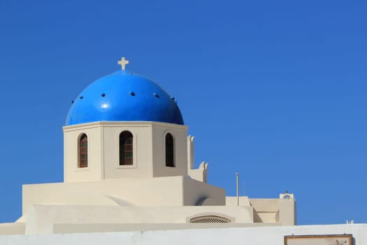 Close up of the blue dome and small cross of a typical orthodox church at Oia by beautiful weather, Santorini, Greece