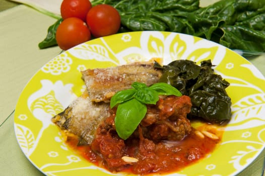 meat rolls in tomato sauce served with boiled spinach
