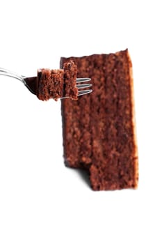 Chocolate cake on fork over a chocolate cake on white background
