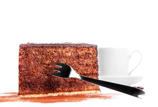 Chocolate cake with fork in front of a cup of coffee on a white background