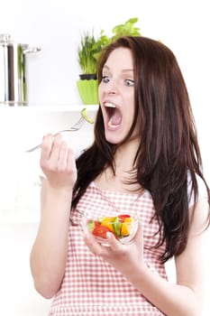 Funny young woman with wide open mouth and eyes eating salad