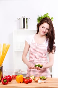 Young laughing woman in the kitchen preparing salad