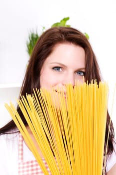 Smiling young woman hiding behind spaghetti