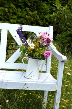 White garden bench on a flower meadow