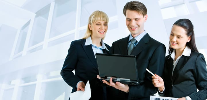 Successful businesspeople looking at the laptop screen on the background of office building