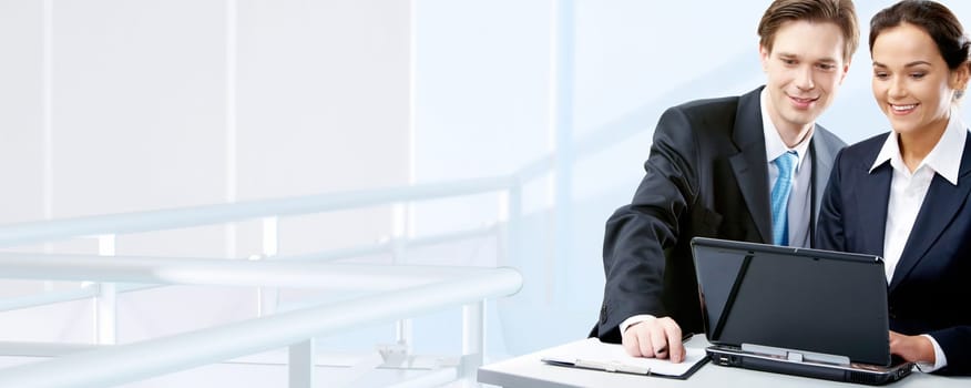Image of two working people looking at laptop screen in office