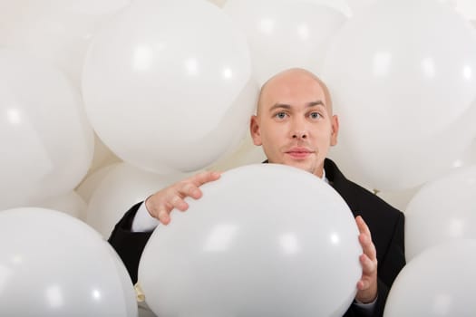 Photo of attractive male holding big white balloon in hands and looking at camera