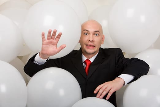 Image of funny man in suit surrounded by balloons looking at camera