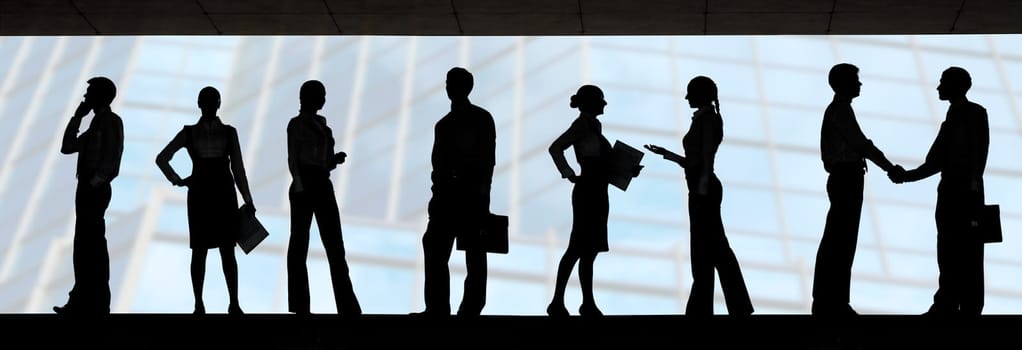 Several silhouettes of businesspeople interacting over blue background