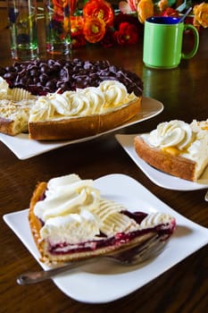 Different Dutch pastry or Limburgian flans with cups, mugs and flowers prepared for a party - vertical