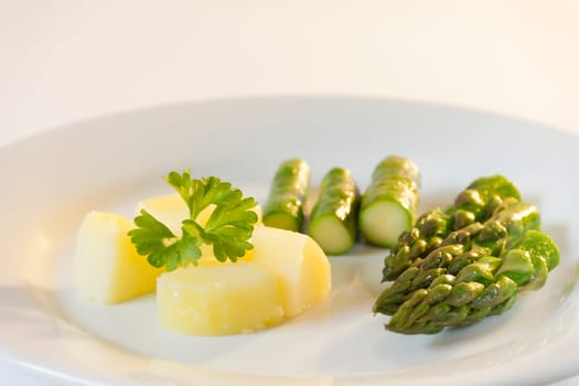 Green asparagus with potato on a white plate