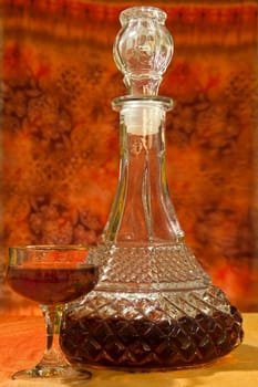 Glass and bottle of brandy with orange gradient background