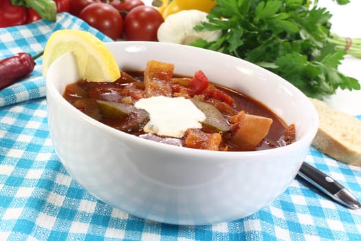 a bowl of solyanka with cream and lemon