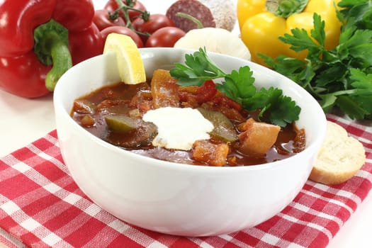 a bowl of solyanka with cream and lemon