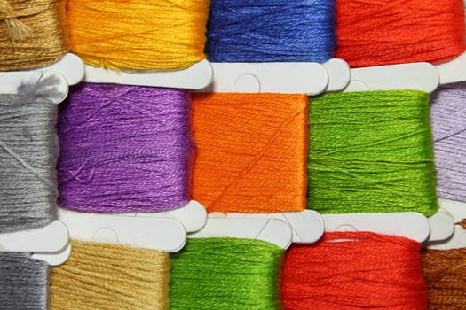 Small reels of coloured threads of red, green, blue and orange.