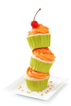 Stacked vanilla cupcakes with orange colored vanilla frosting