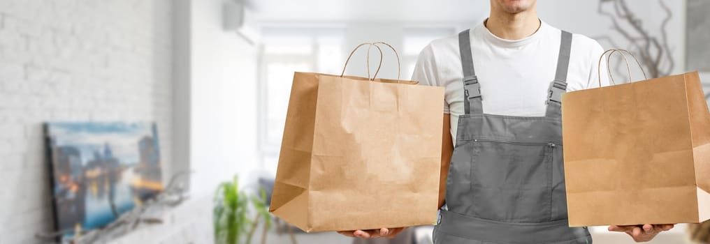 Paper pocket and food containers in hands of a smiling deliveryman. .Quality service of a restaurant