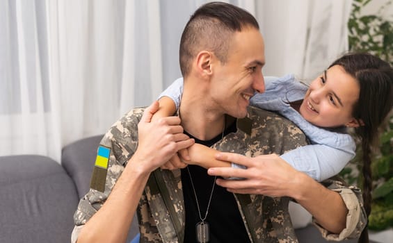 Soldier in Ukrainian military uniform hugging his daughter. Family reunion.