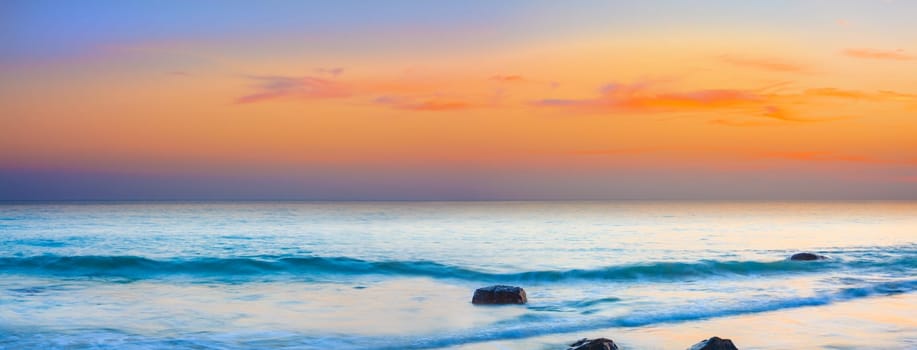 Sunset over the sea. Stone on the foreground. Panorama