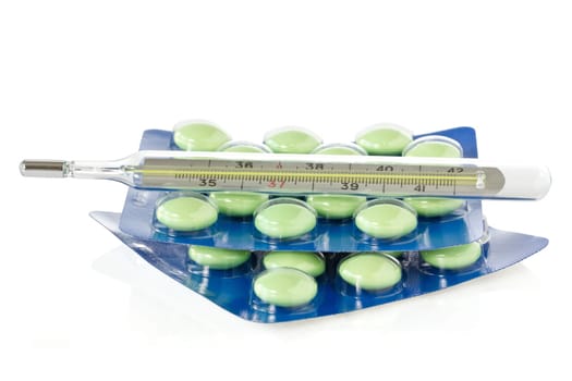 Thermometer and pills over a  white  background