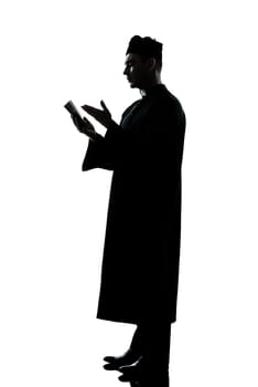 one caucasian man priest reading bible silhouette in studio isolated on white background