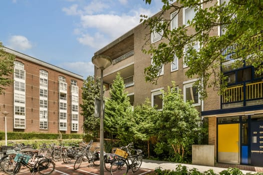 some bikes parked on the side of a street in front of an apartment building with blue sky and white clouds